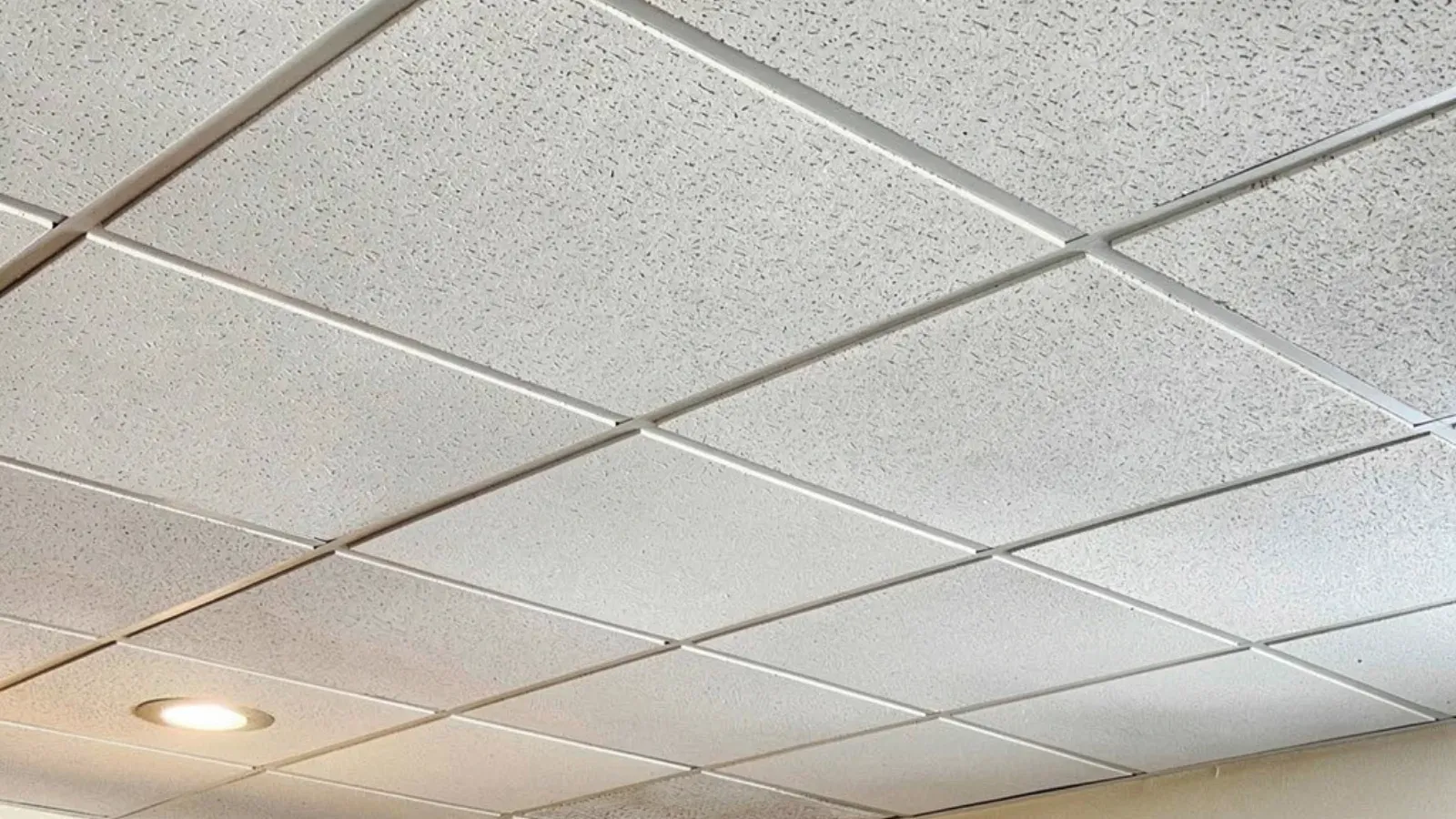 A suspended acoustic tile ceiling with every panel set into a white T-bar grid