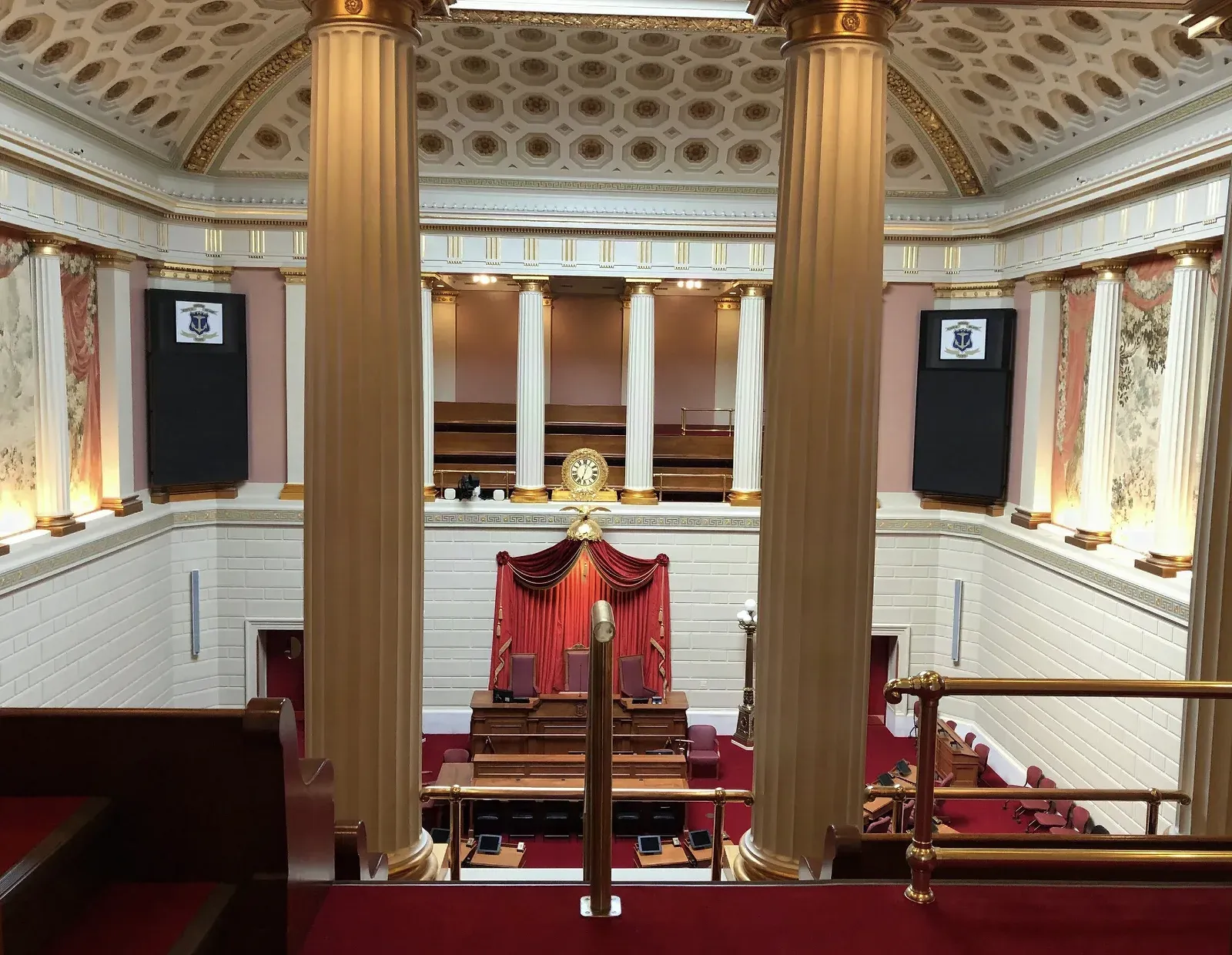 Ornate Rhode Island State House legislative chamber with fluted columns, a coffered plaster dome, and plaster-finished walls above the rostrum