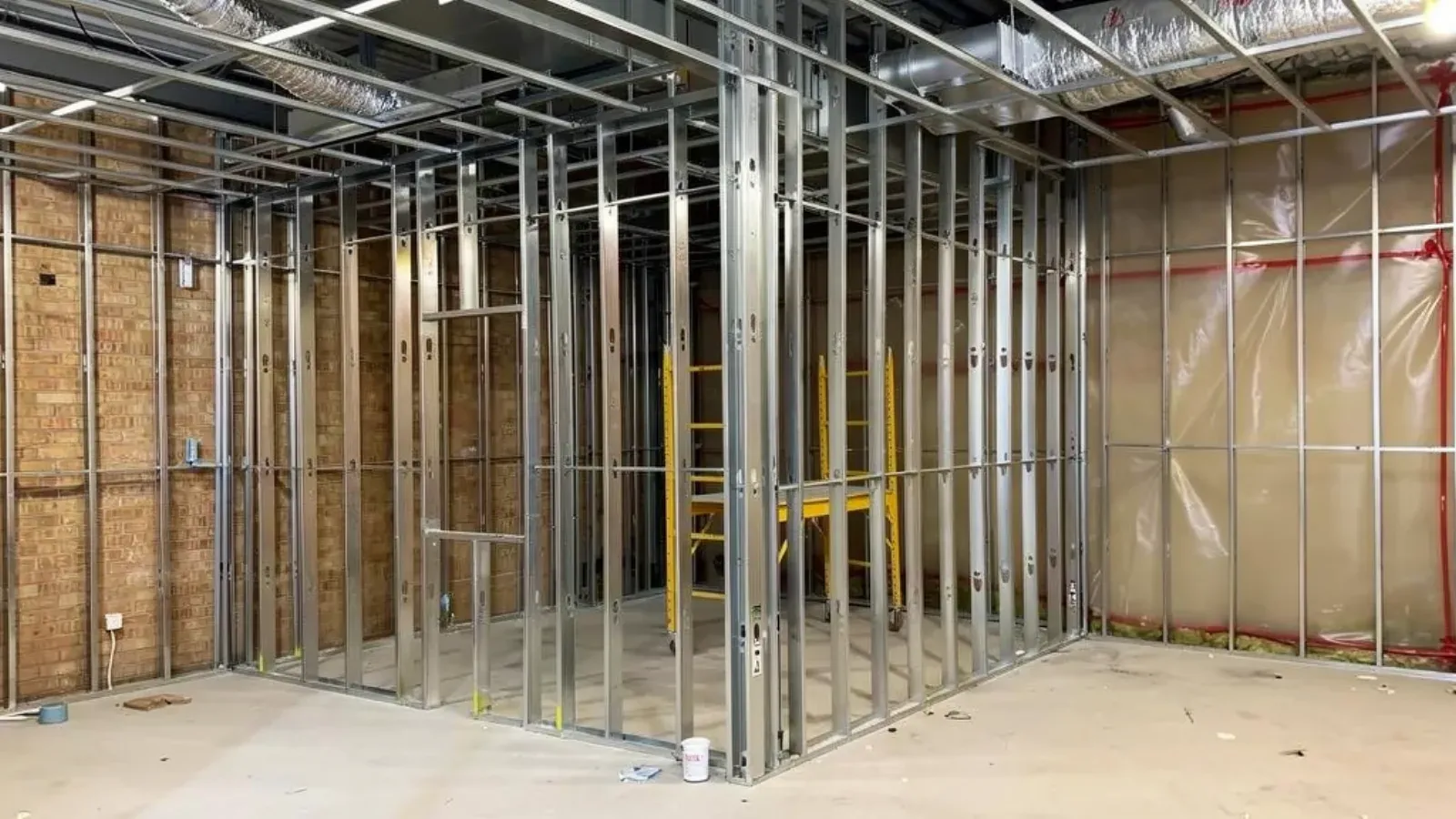 Steel stud partition walls framed inside an unfinished commercial interior, with overhead ceiling framing and ductwork
