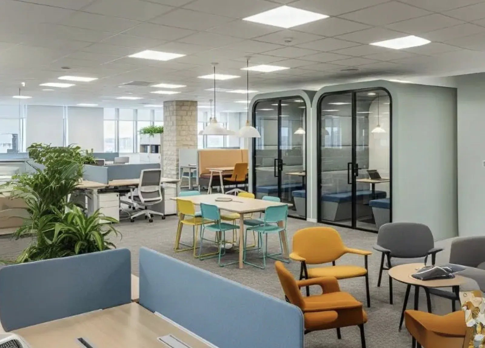 Open-plan office with a finished drywall and drop-tile ceiling, upholstered meeting pods, and collaborative seating